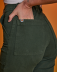 Close up of Alex's hand in the back pocket of Paintstamped Work Pants in Cactus