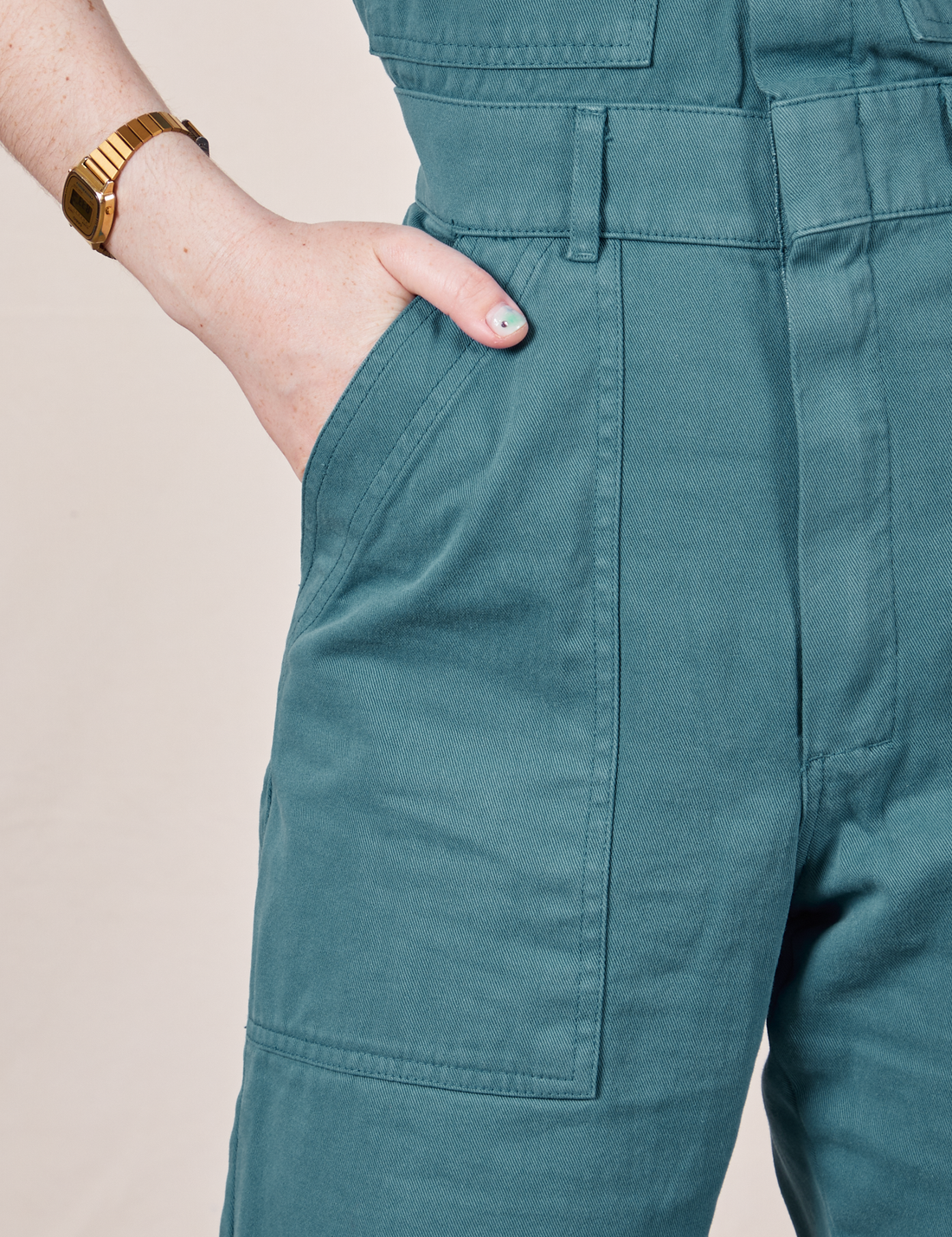Front pocket close up of Petite Short Sleeve Jumpsuit in Marine Blue. Hana has her hand in the pocket.