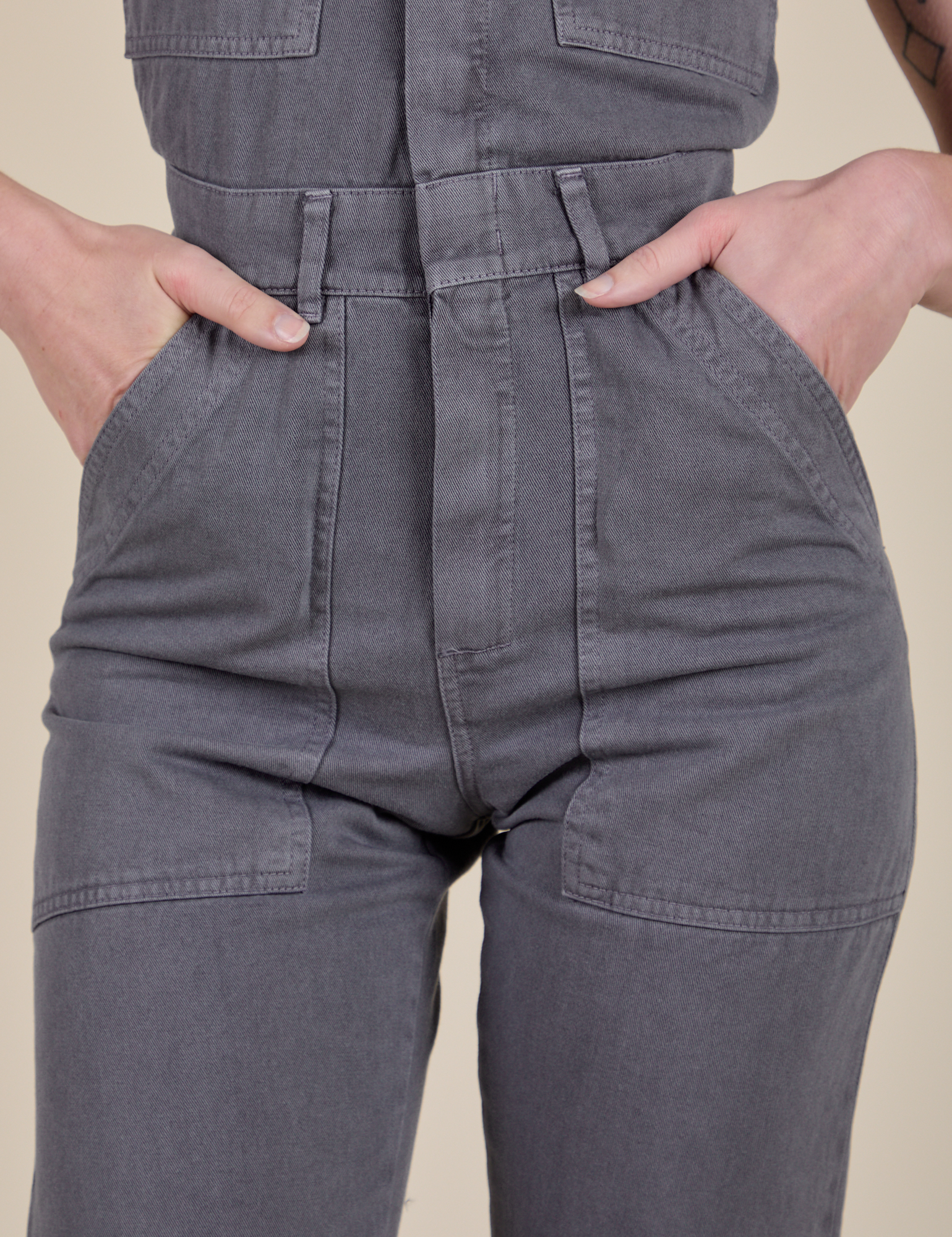 Short Sleeve Jumpsuit in Washed Grey close up with Alex's hand in the front pockets