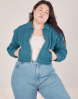 Ashley is wearing the Ricky Jacket in Marine Blue, a vintage off-white Tank Top and light wash Frontier Jeans. Both her hands are in the pockets.