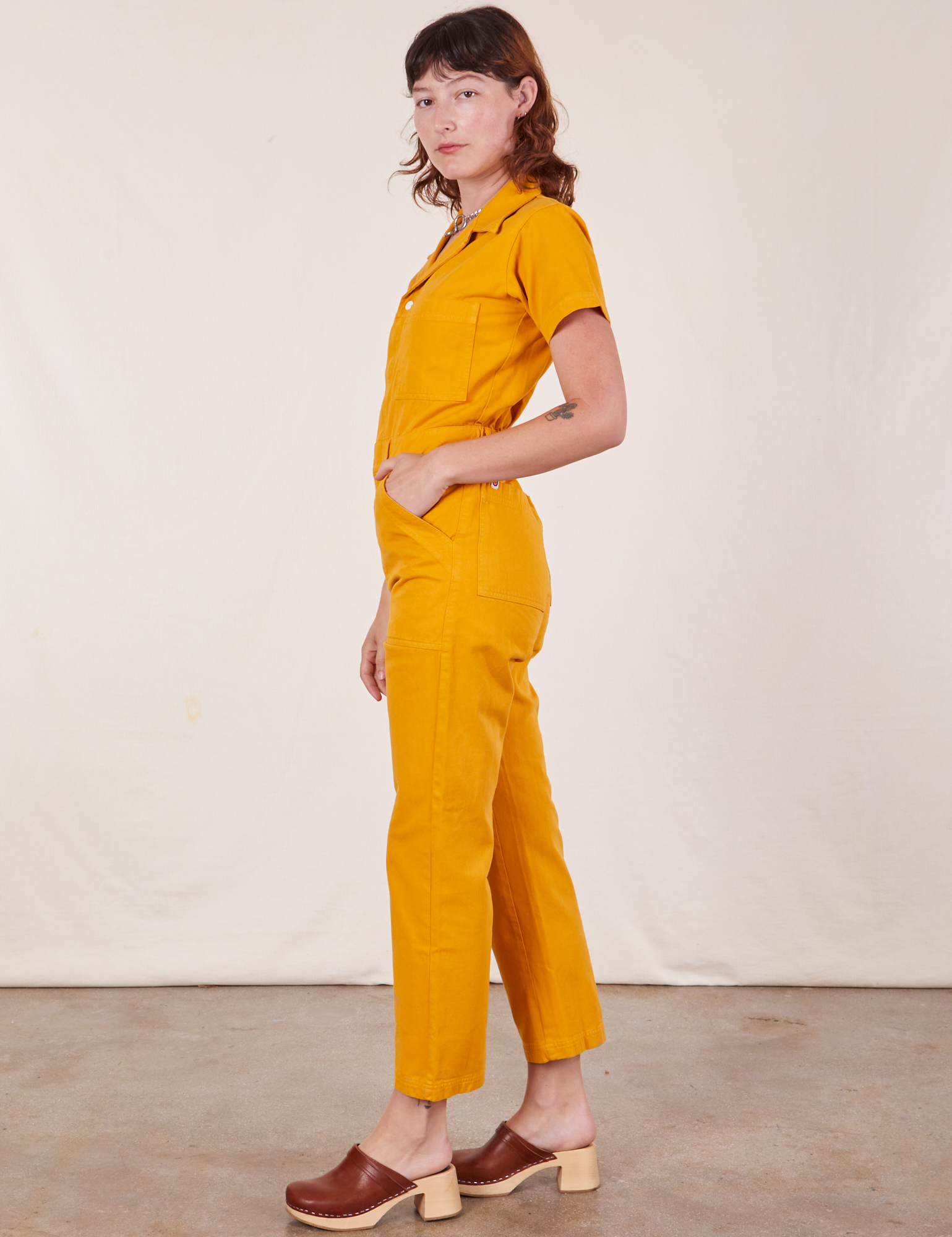 Side view of Short Sleeve Jumpsuit in Mustard Yellow worn by Alex