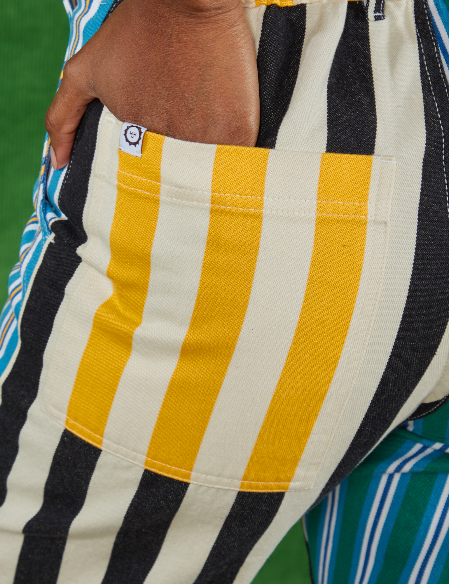 Mismatched Stripe Work Pants back pocket close up. Kandia has her hand in the pocket.