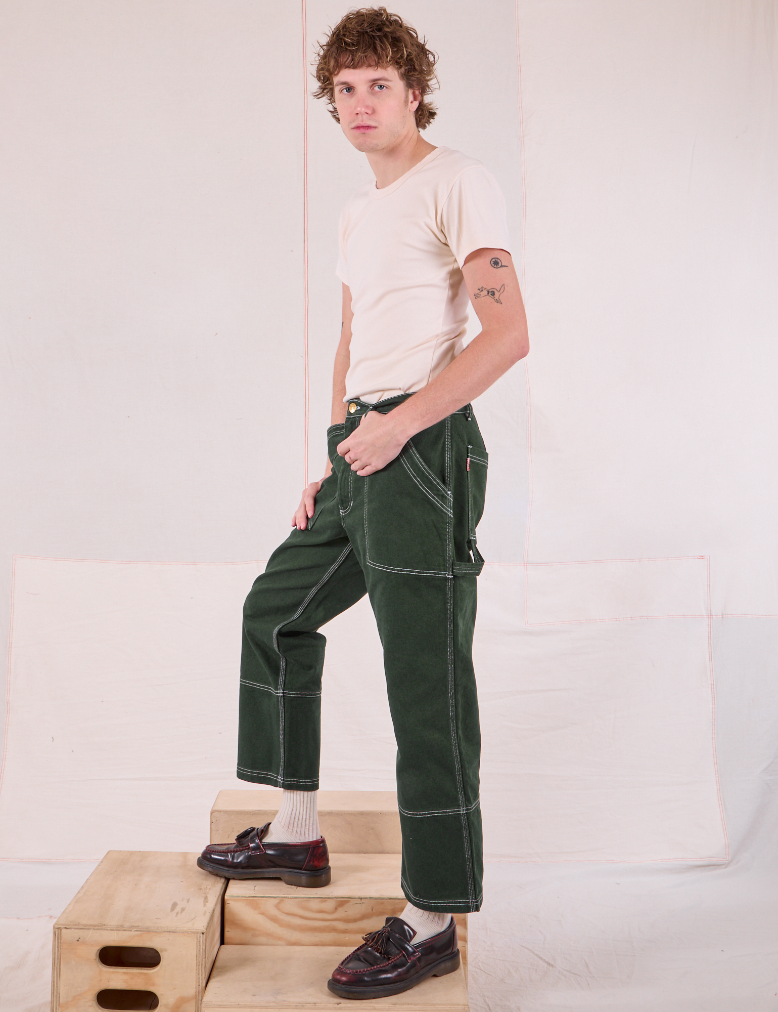 Side view of Carpenter Jeans in Swamp Green and Organic Vintage Tee in Vintage Tee Off-White on Quinn