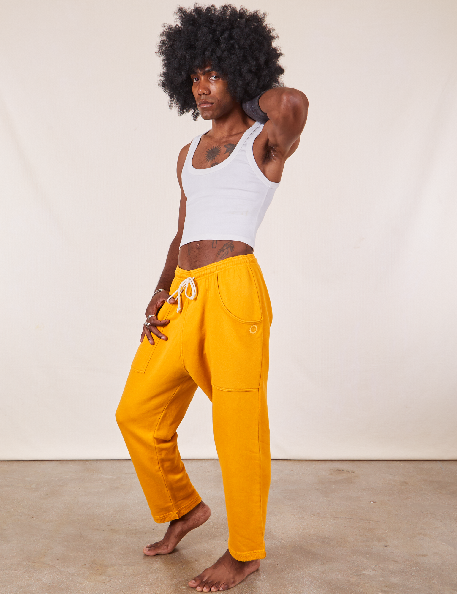 Angled view of Cropped Rolled Cuff Sweatpants in Mustard Yellow and vintage off-white Tank Top on Jerrod