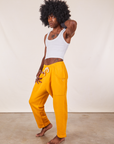 Angled view of Cropped Rolled Cuff Sweatpants in Mustard Yellow and vintage off-white Tank Top on Jerrod
