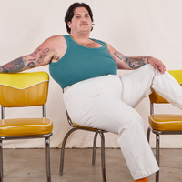 Sam is sitting on a yellow chair wearing Tank Top in Marine Blue and vintage off-white Western Pants