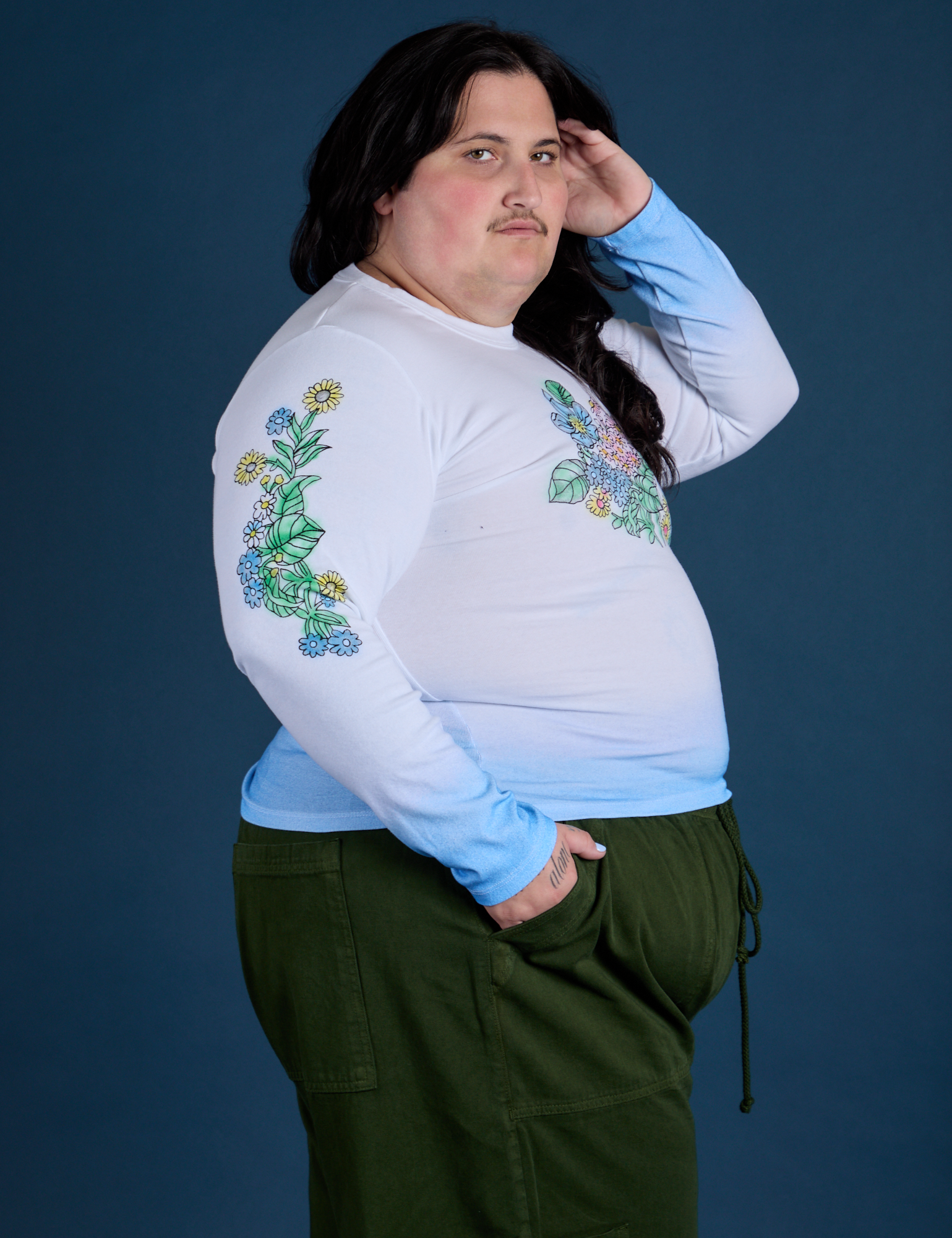 Side view of Floral Long Sleeve Baby Tee in Baby Blue and evergreen Drop Pocket Cargo Pants on Sam