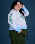 Side view of Floral Long Sleeve Baby Tee in Baby Blue and evergreen Drop Pocket Cargo Pants on Sam