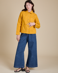 Alex is wearing Denim Work Jacket in Mustard Yellow and dark wash Indigo Wide Leg Trousers