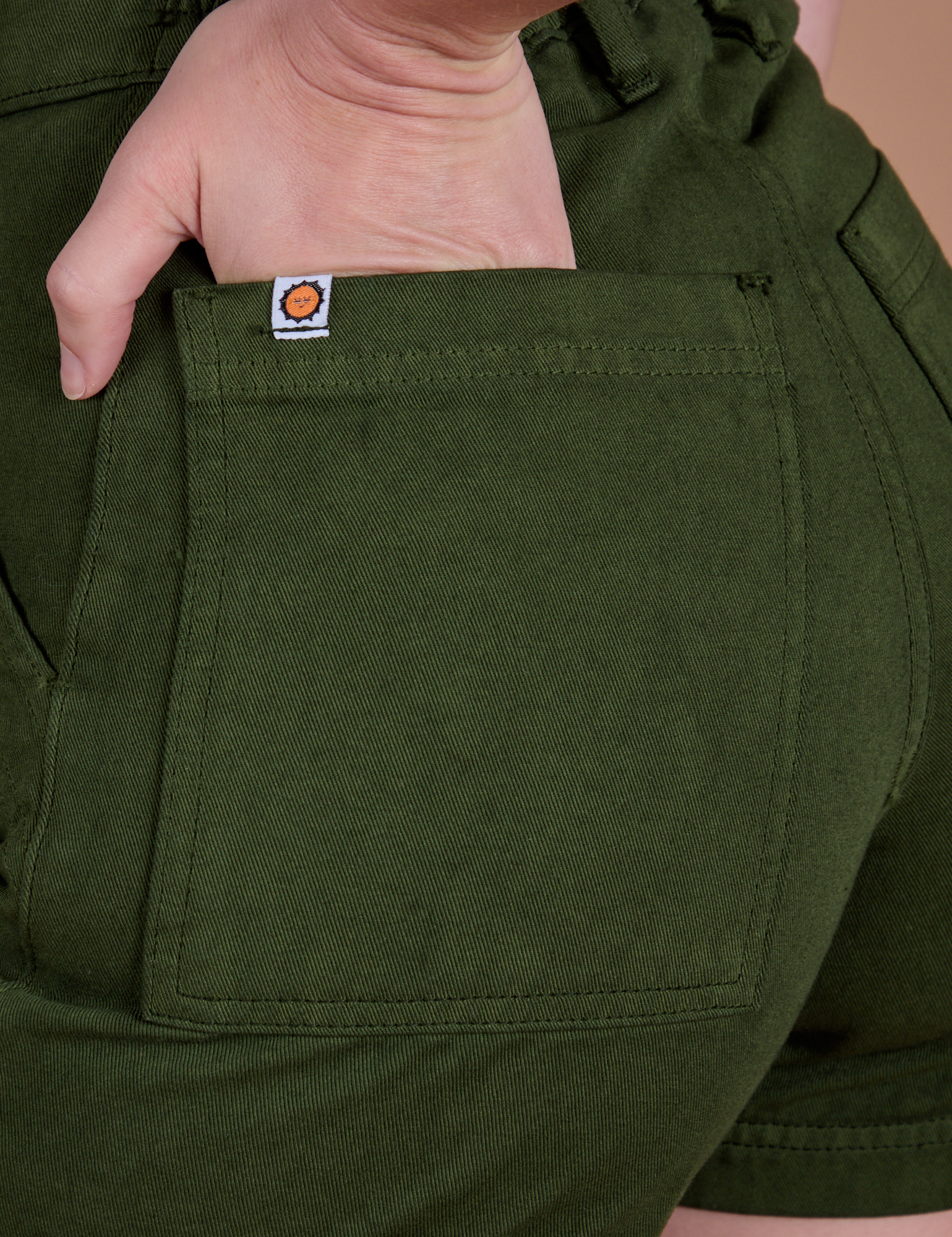 Close up of Alex's hand in the back pocket of Classic Work Shorts in Evergreen