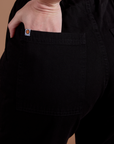 Close up of Alex's hand in the back pocket of Action Pants in Basic Black