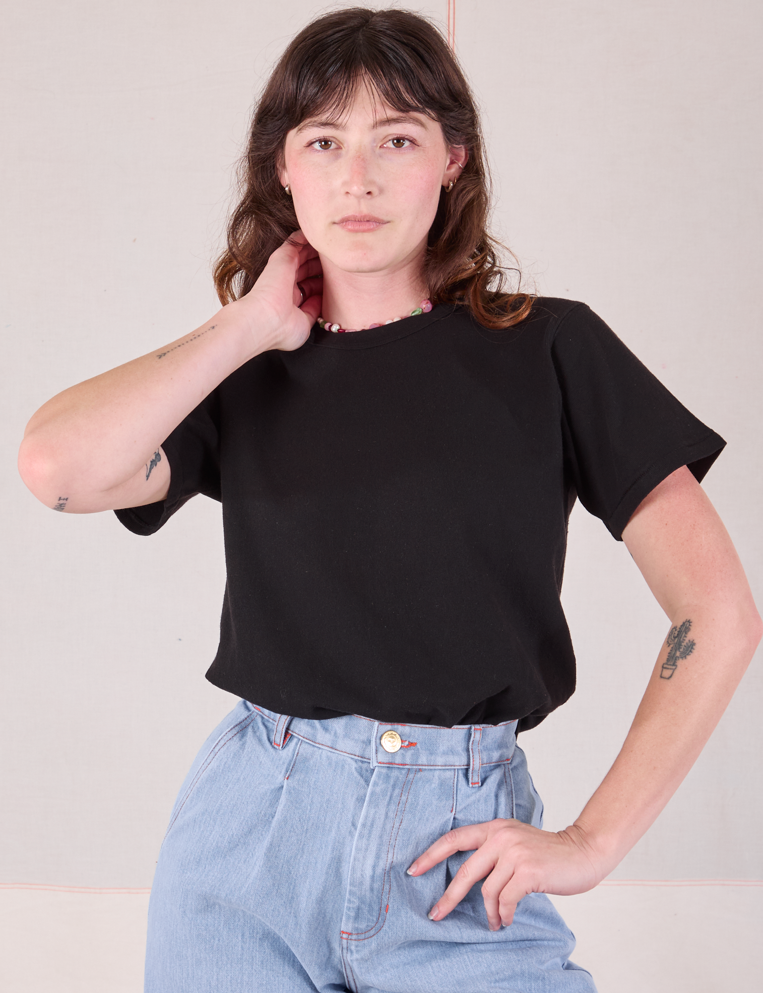 Alex is wearing Burly Tee in Basic Black tucked into her light wash Denim Wide Leg Trousers