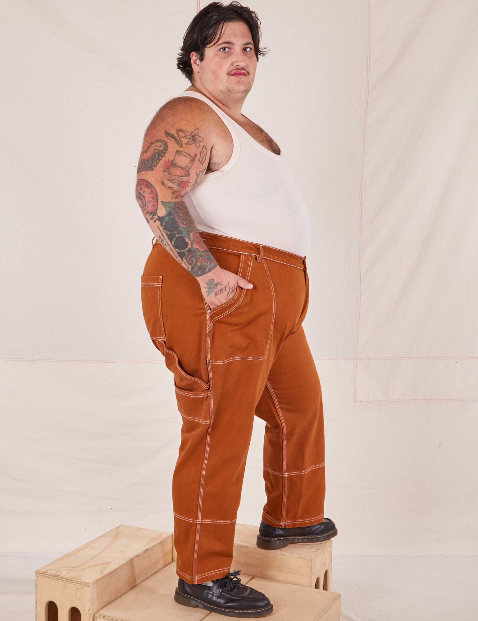 Side view of Carpenter Jeans in Burnt Terracotta and vintage off-white Cropped Tank Top on Sam