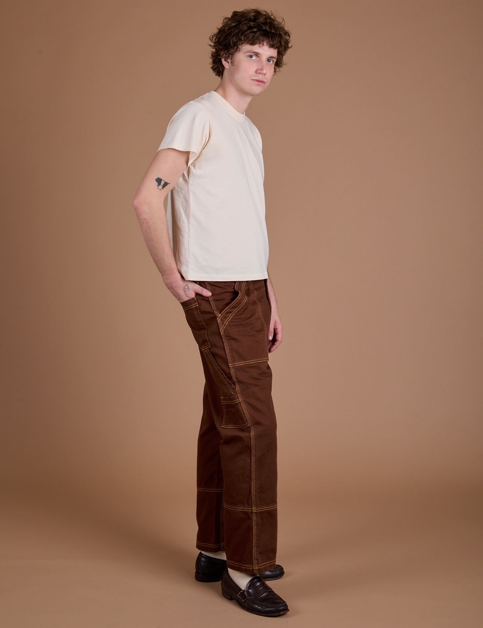 Side view of Carpenter Jeans in Fudgesicle Brown and Organic Vintage Tee in Vintage Tee Off-White on Quinn