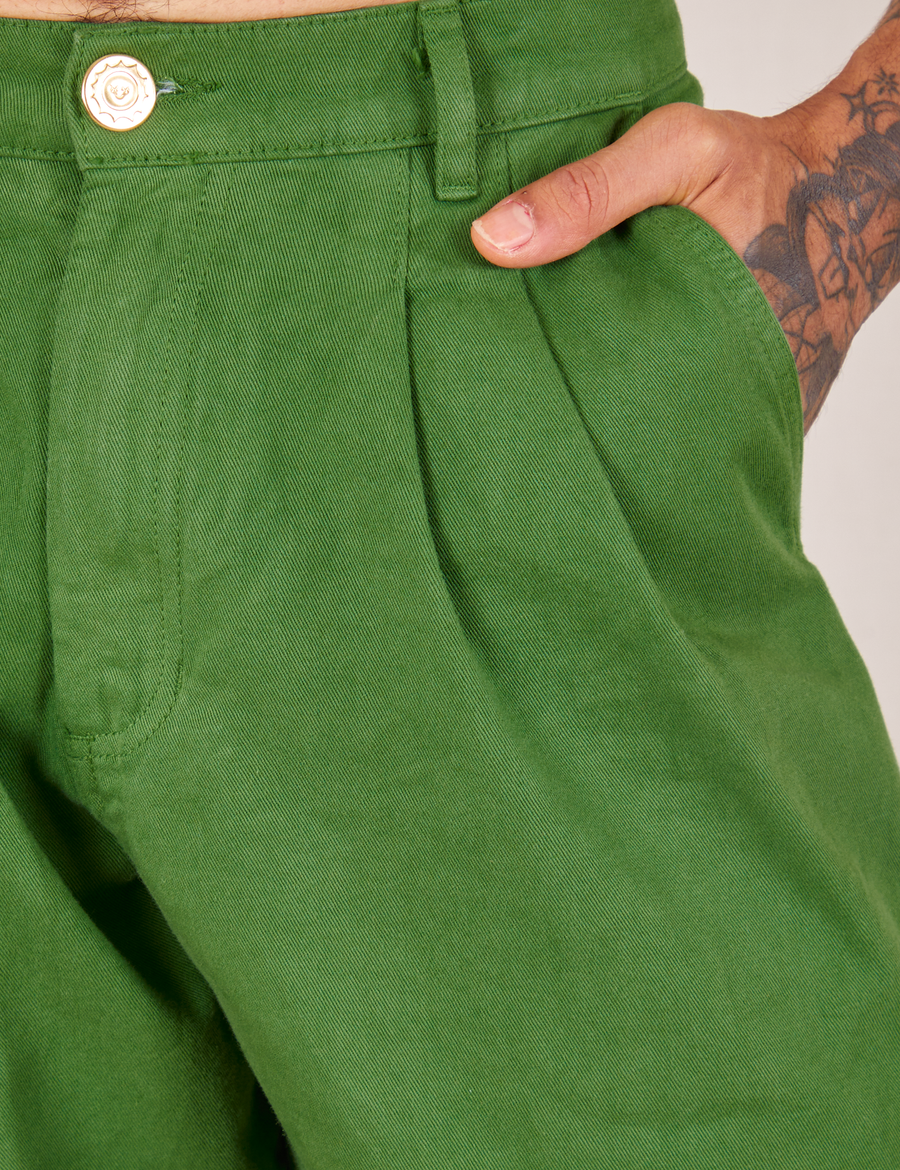 Front pocket close up of Heavyweight Trousers in Lawn Green. Jesse has their hand in the pocket.