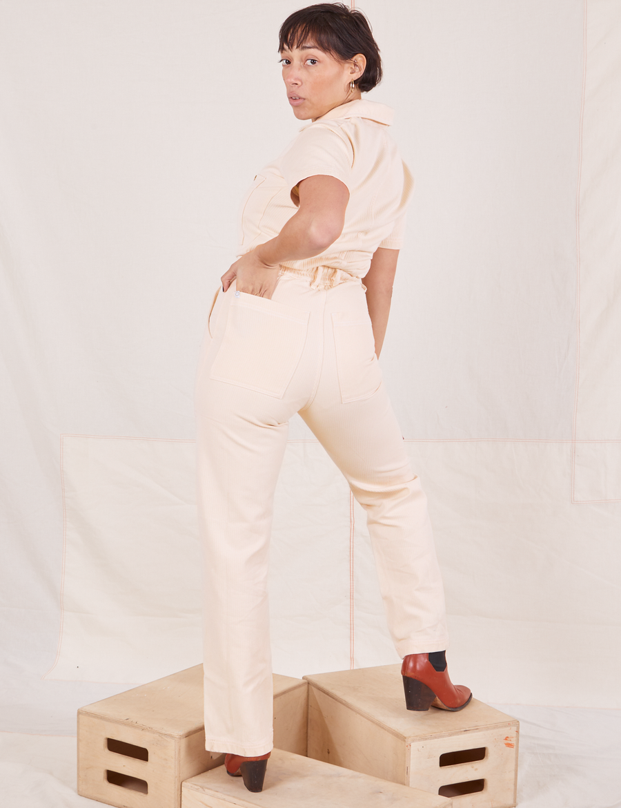 Heritage Short Sleeve Jumpsuit in Natural back view. Worn by Tiara with left hand in left back pocket