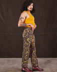 Side view of Marble Splatter Work Pants in Espresso Brown and mustard yellow Tank Top on Jesse