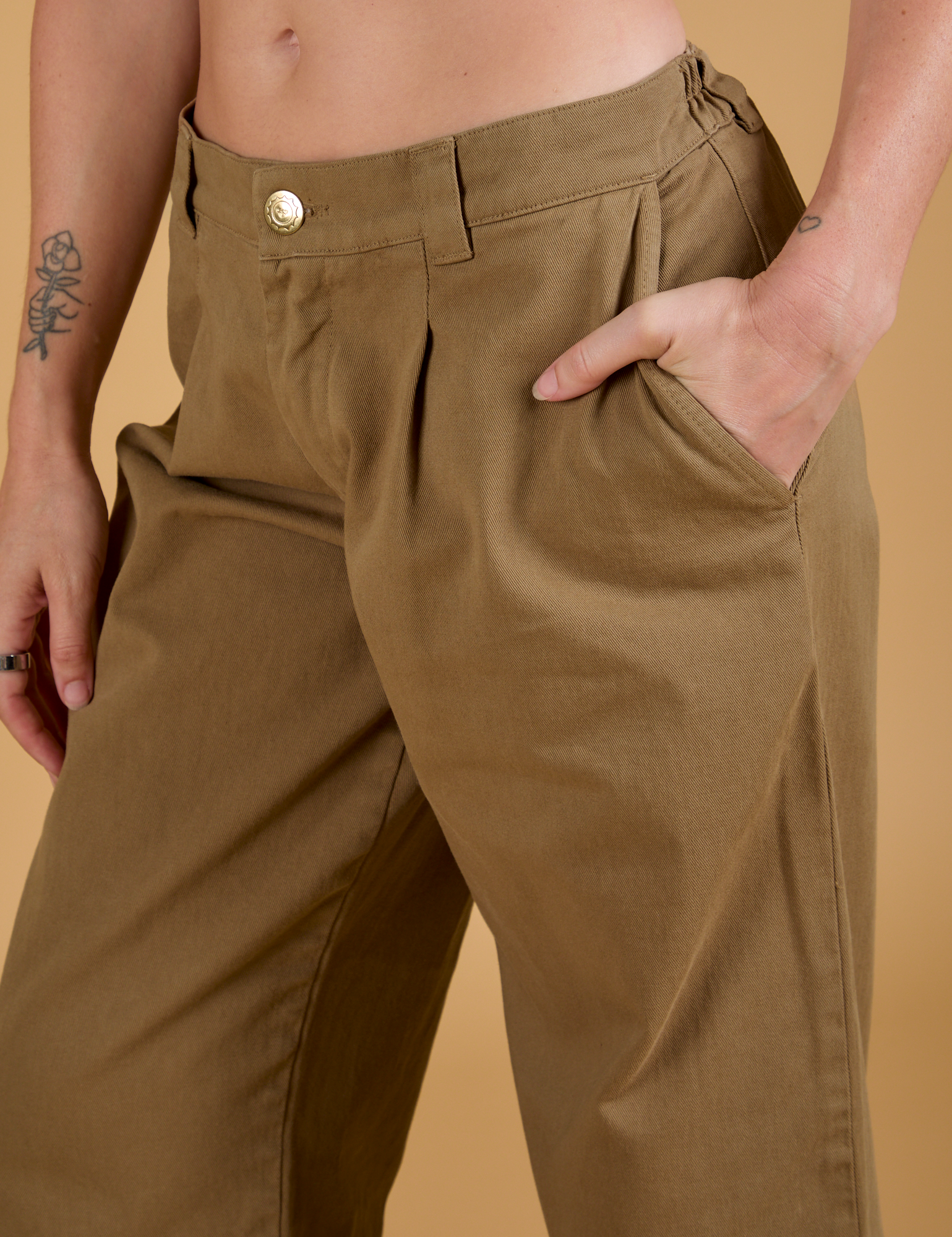 Close up of Alex&#39;s hand in the front pocket of Baggy Mid-Rise Trousers in Desert Brown