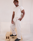 Angled front view of Mid-Rise Pleated Trousers in Stone White and Organic Vintage Tee in vintage tee off-white