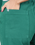 Column Work Pants in Hunter Green back pocket close up. Tiara has her hand in the pocket.