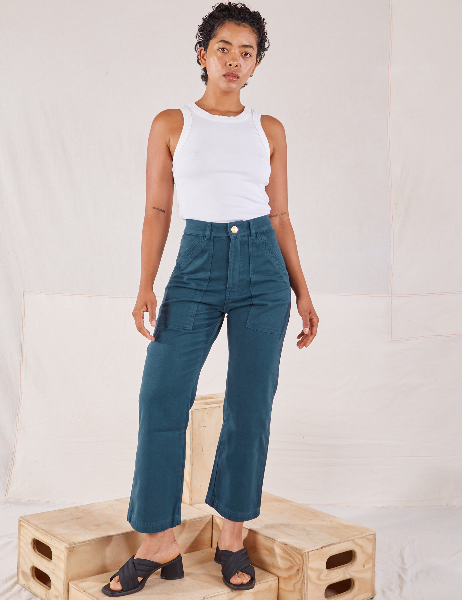 Mika is 5&#39;1&quot; and wearing Petite XXS Organic Work Pants in Lagoon paired with Racerback Tank in vintage tee off-white