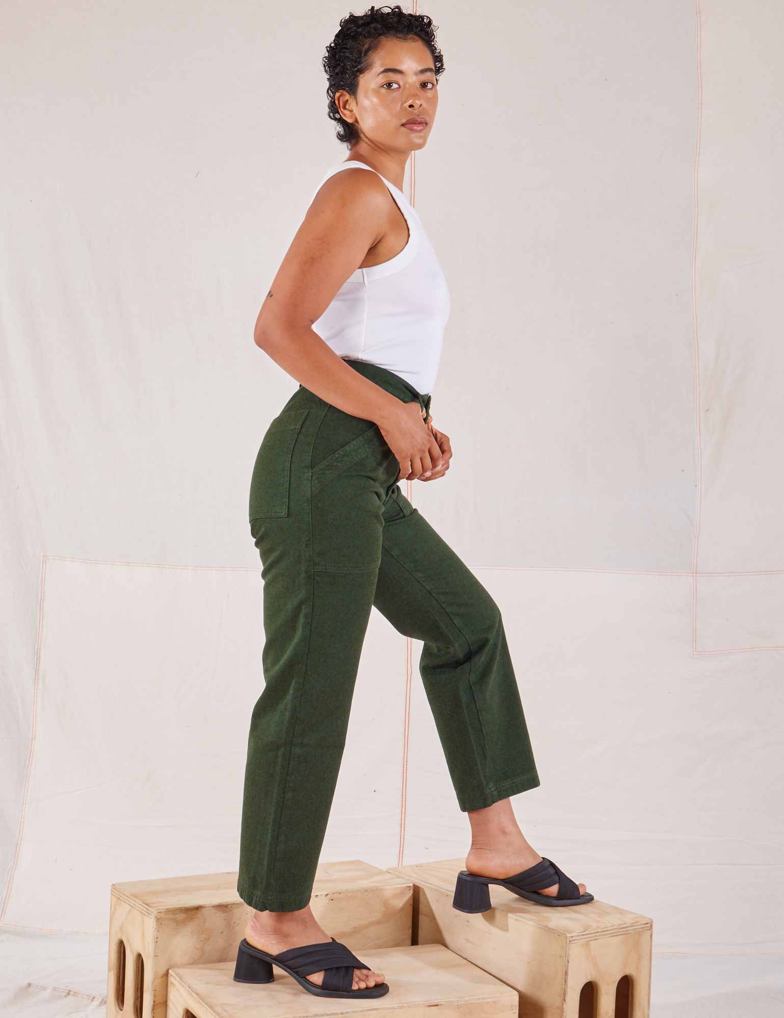 Side view of Organic Work Pants in Swamp Green and Racerback Tank in vintage tee off-white on Mika