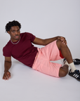 Isaac is wearing Longline Work Shorts in Baby Pink and Organic Vintage Tee in Red Wine