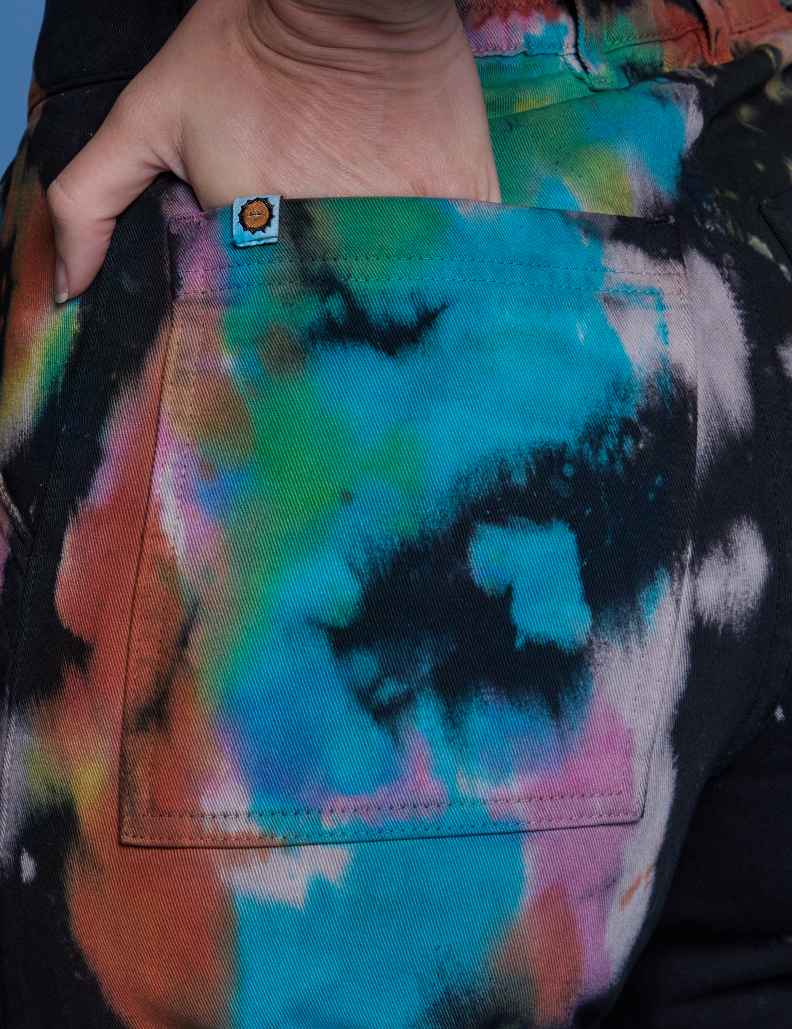 Close up of Alex&#39;s hand in the back pocket of Work Pants in Rainbow Magic Waters