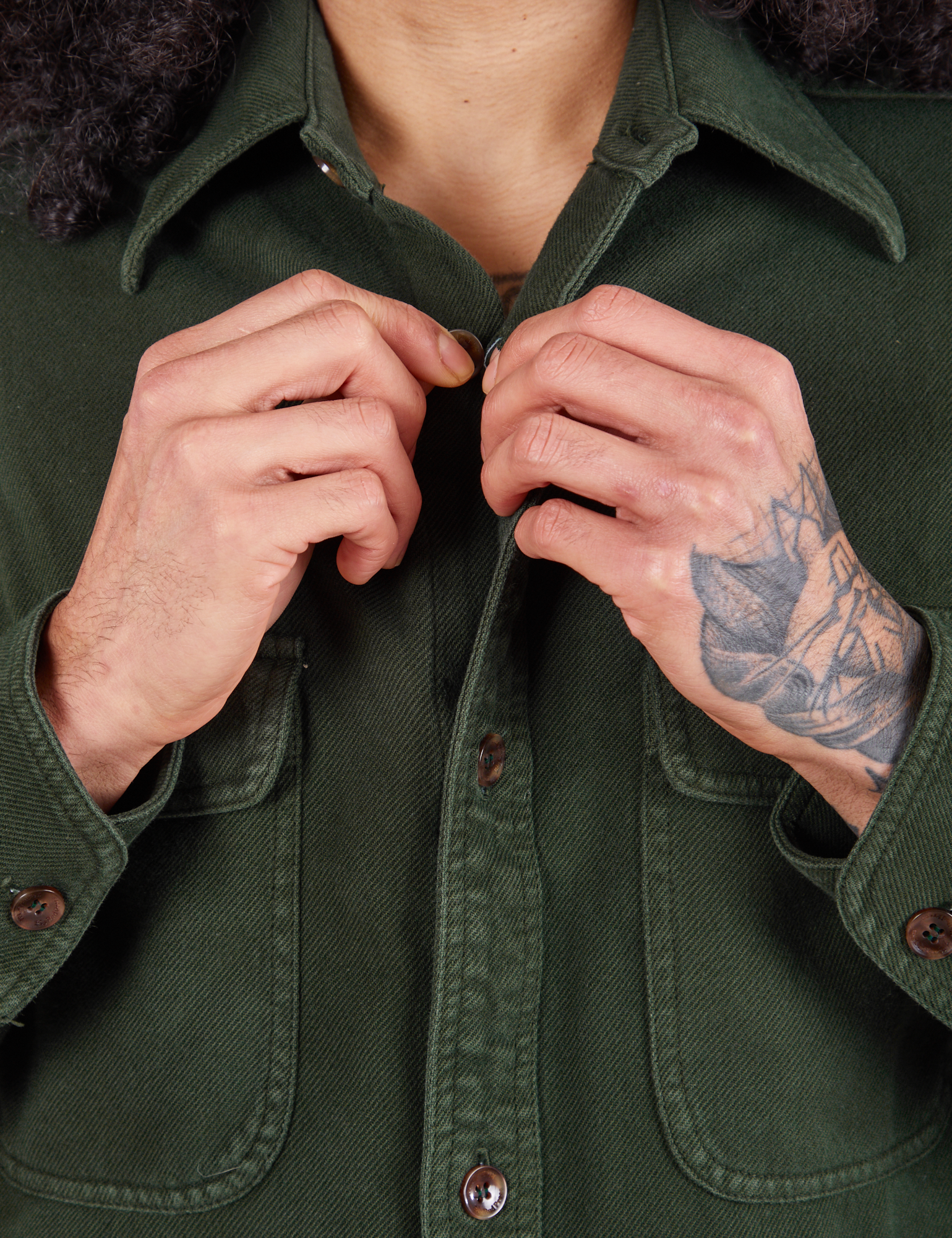 Flannel Overshirt in Swamp Green front close up. Jesse is buttoning up the shirt