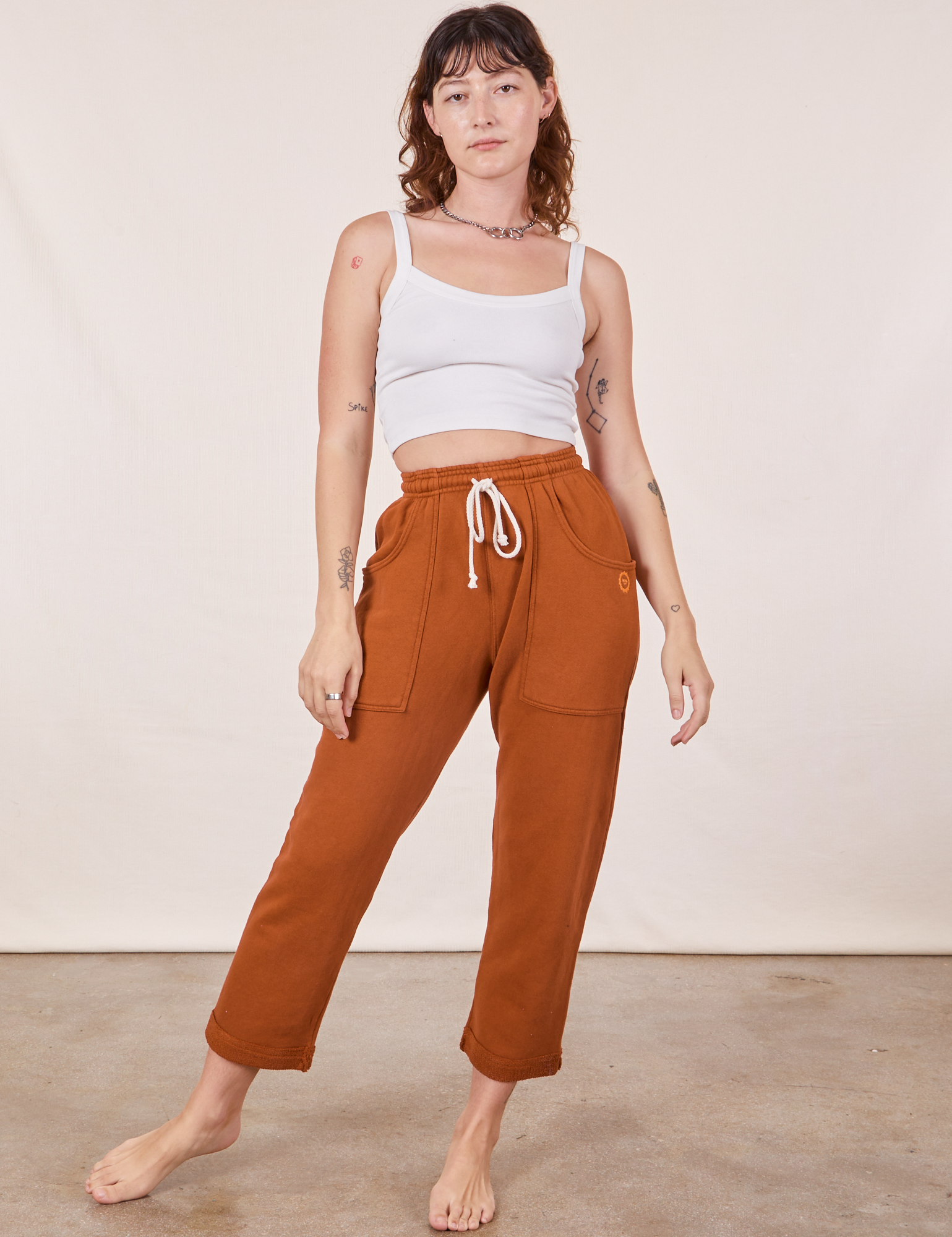 Alex is wearing Cropped Rolled Cuff Sweatpants in Burnt Terracotta and vintage off-white Cami