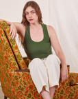 Allison is sitting in a floral upholstered chair wearing Tank Top in Dark Emerald Green and vintage off-white Western Pants