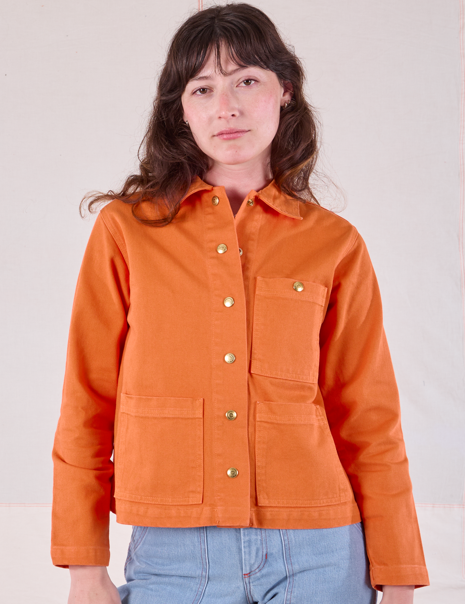 Alex is wearing a buttoned up Denim Work Jacket in Construction Orange