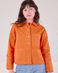 Alex is wearing a buttoned up Denim Work Jacket in Construction Orange