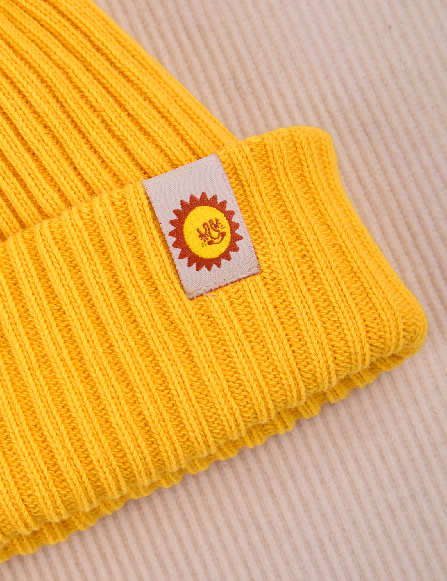 Ribbed Beanie in Golden Yellow close up of sun baby tag