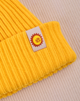 Ribbed Beanie in Golden Yellow close up of sun baby tag