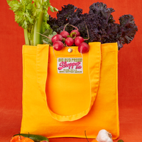 Shopper Tote Bag in Sunshine Yellow with lettuce, celery and radishes in bag. Peppers, cucumber and garlic are place in front of the tote.