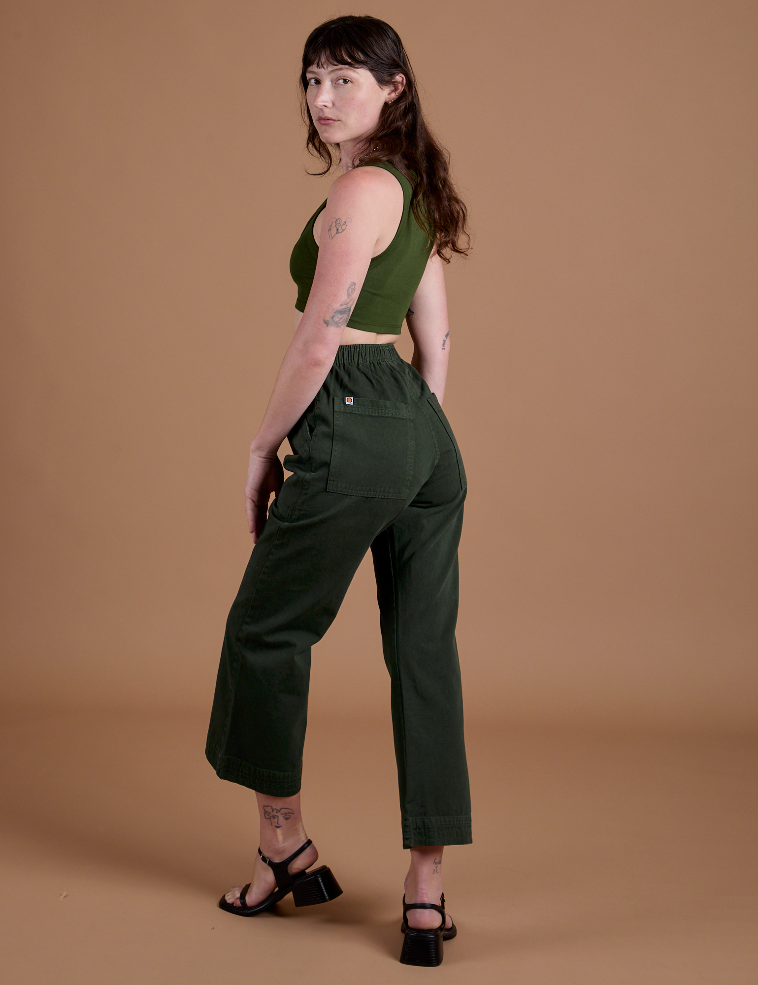 Angled back view of Action Pants in Swamp Green and evergreen Mini Tank on Alex