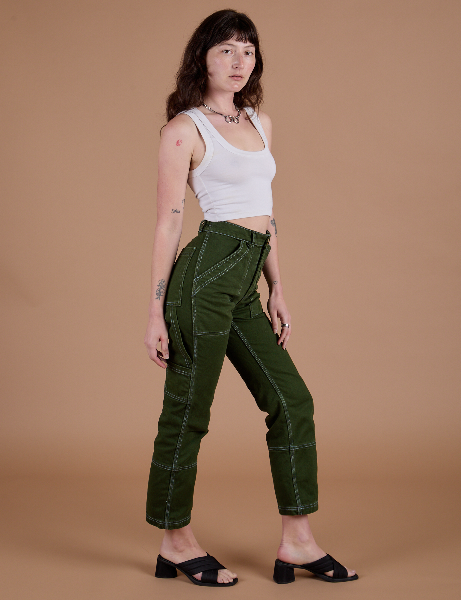 Angled front view of Carpenter Jeans in Evergreen and Cropped Tank in Vintage Tee White on Alex