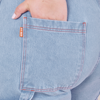 Back pocket close up of Carpenter Jeans in Light Wash. Ashley has her hand tucked into the pocket.