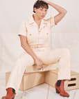 Heritage Short Sleeve Jumpsuit in Natural on Tiara sitting on wooden crate
