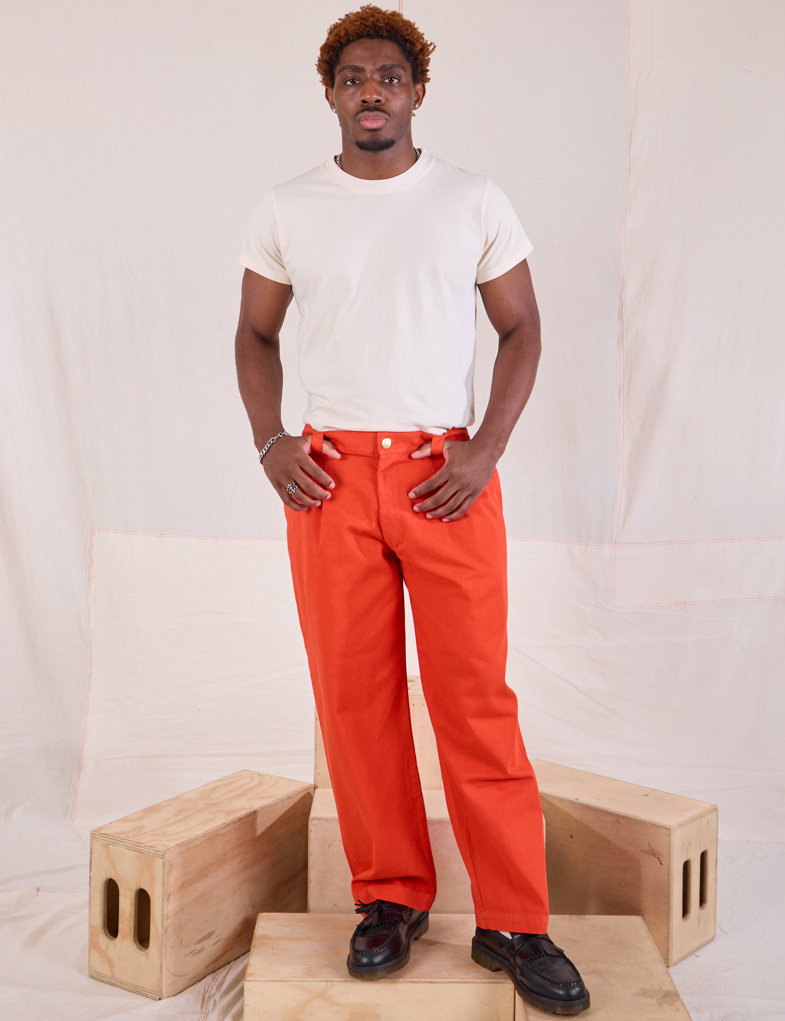 Issac is 5&#39;10&quot; and wearing M Mid-Rise Pleated Trousers in Chili Red paired with an Organic Vintage Tee in vintage tee off-white