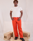 Issac is 5'10" and wearing M Mid-Rise Pleated Trousers in Chili Red paired with an Organic Vintage Tee in vintage tee off-white