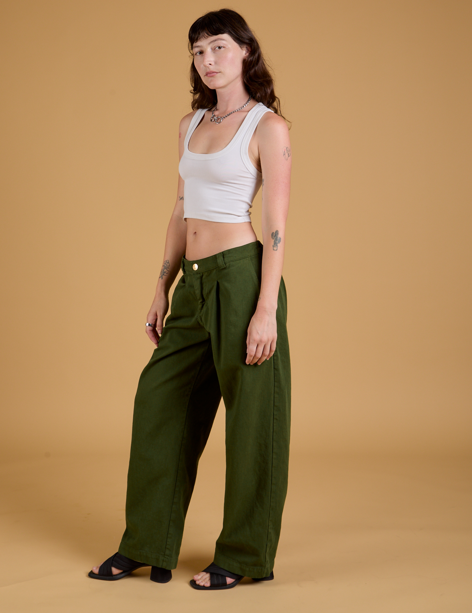 Angled front view of Baggy Mid-Rise Trousers in Evergreen and vintage tee white Cropped Tank on Alex