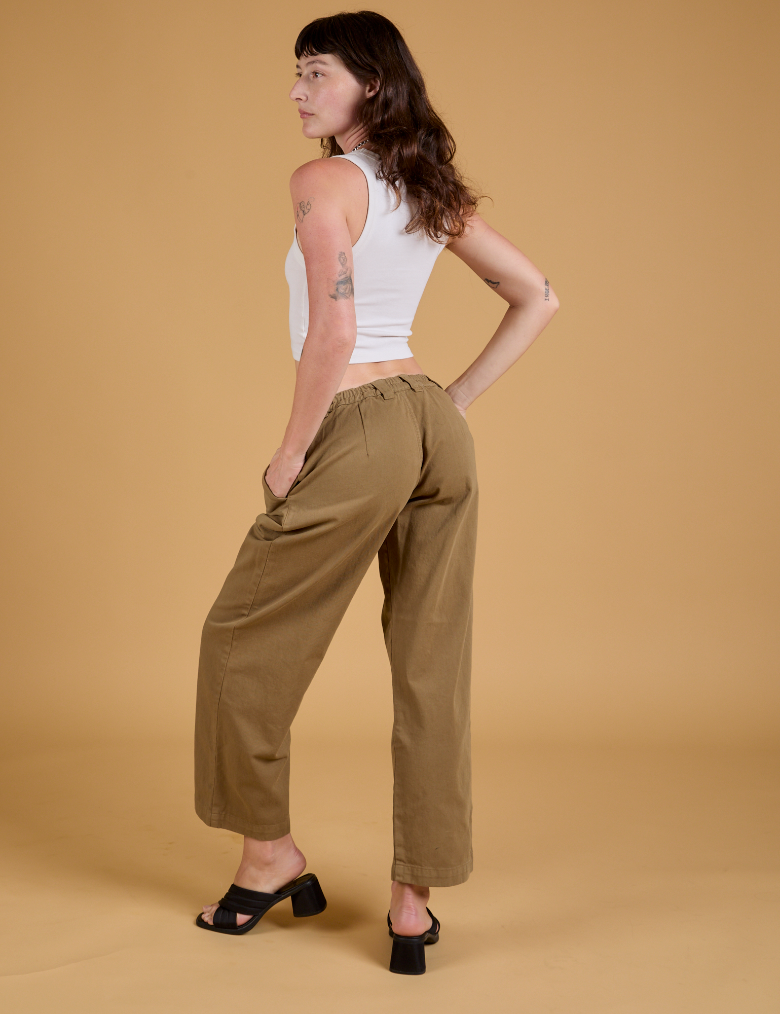 Angled back view of Baggy Mid-Rise Trousers in Desert Brown and vintage tee white Cropped Tank on Alex