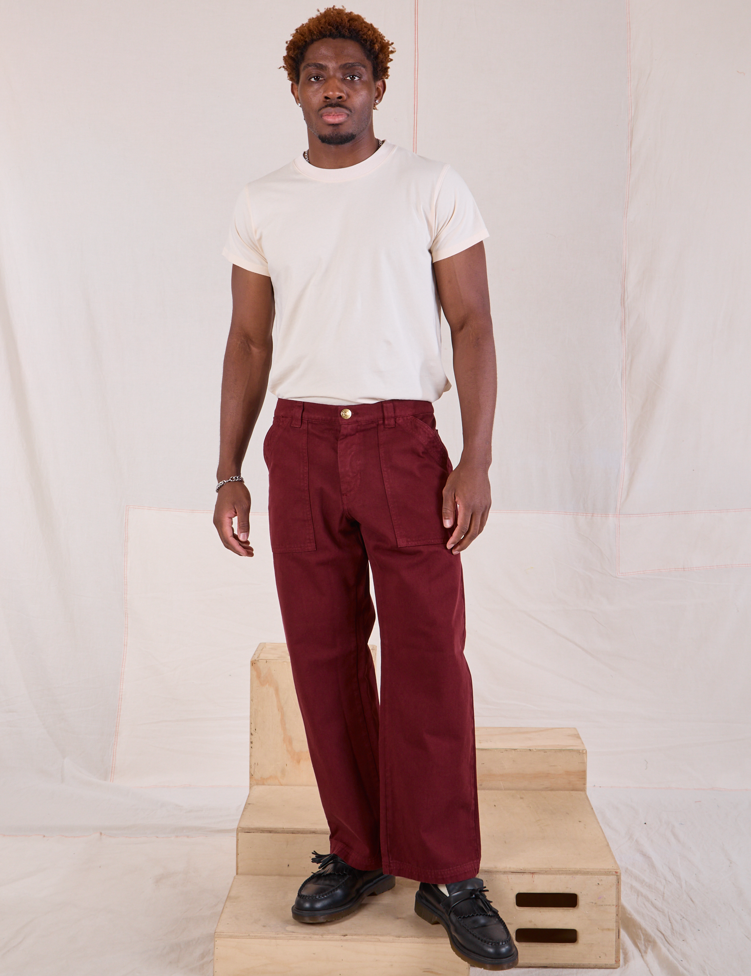 Issac is 5&#39;10&quot; and wearing M Mid-Rise Work Pants in Red Wine paired with Organic Vintage Tee in vintage tee off-white