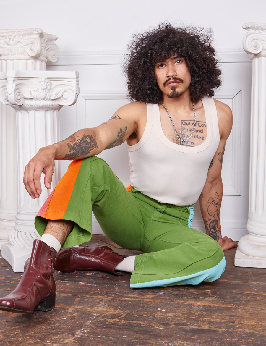 Jesse is sitting on the floor wearing Hand-Painted Stripe Western Pants in Bright Olive and a vintage off-white Tank Top