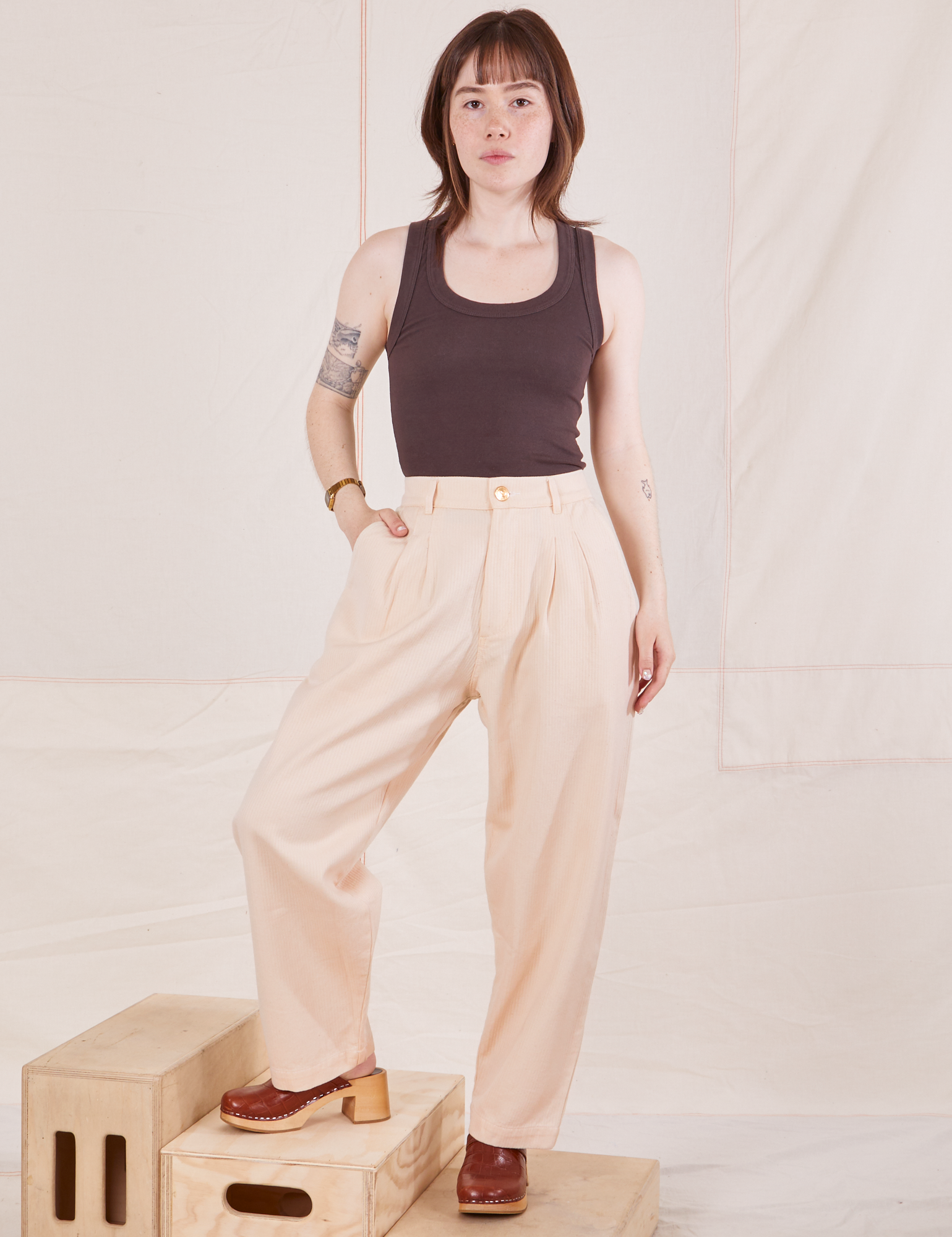 Hana is 5&#39;3&quot; and wearing XXS Petite Heritage Trousers in Vintage Off-White paired with espresso brown Tank Top