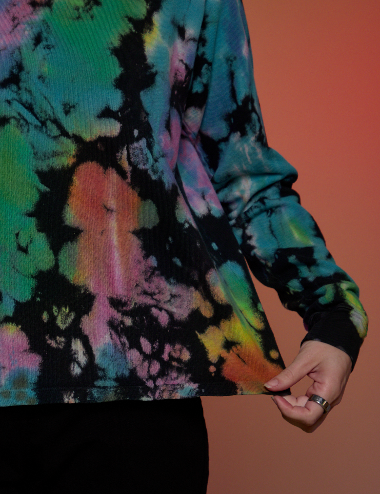 Magic Waters Long Sleeve Burly Tee in Rainbow bottom close up with Alex tugging on the hem