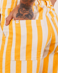 Work Pants in Lemon Stripe back pocket close up. Jesse has their hand in the pocket.
