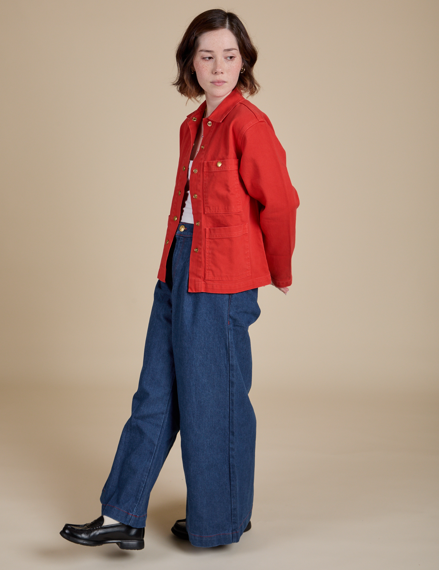 Side view of Denim Work Jacket in Mustang Red and dark wash Indigo Wide Leg Trouser on Hana